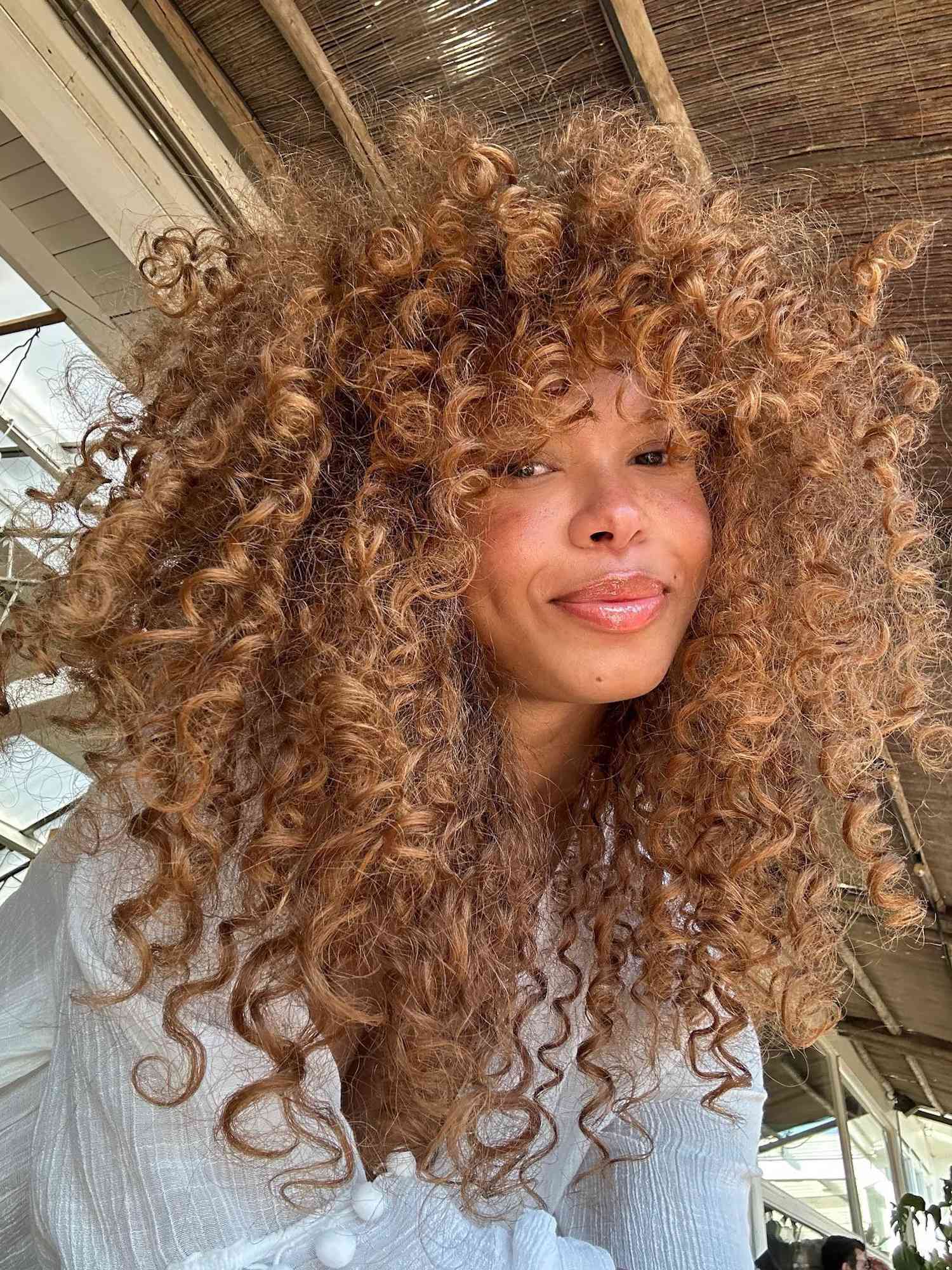 Woman with curly ginger hair, radiant skin, and glossy lips