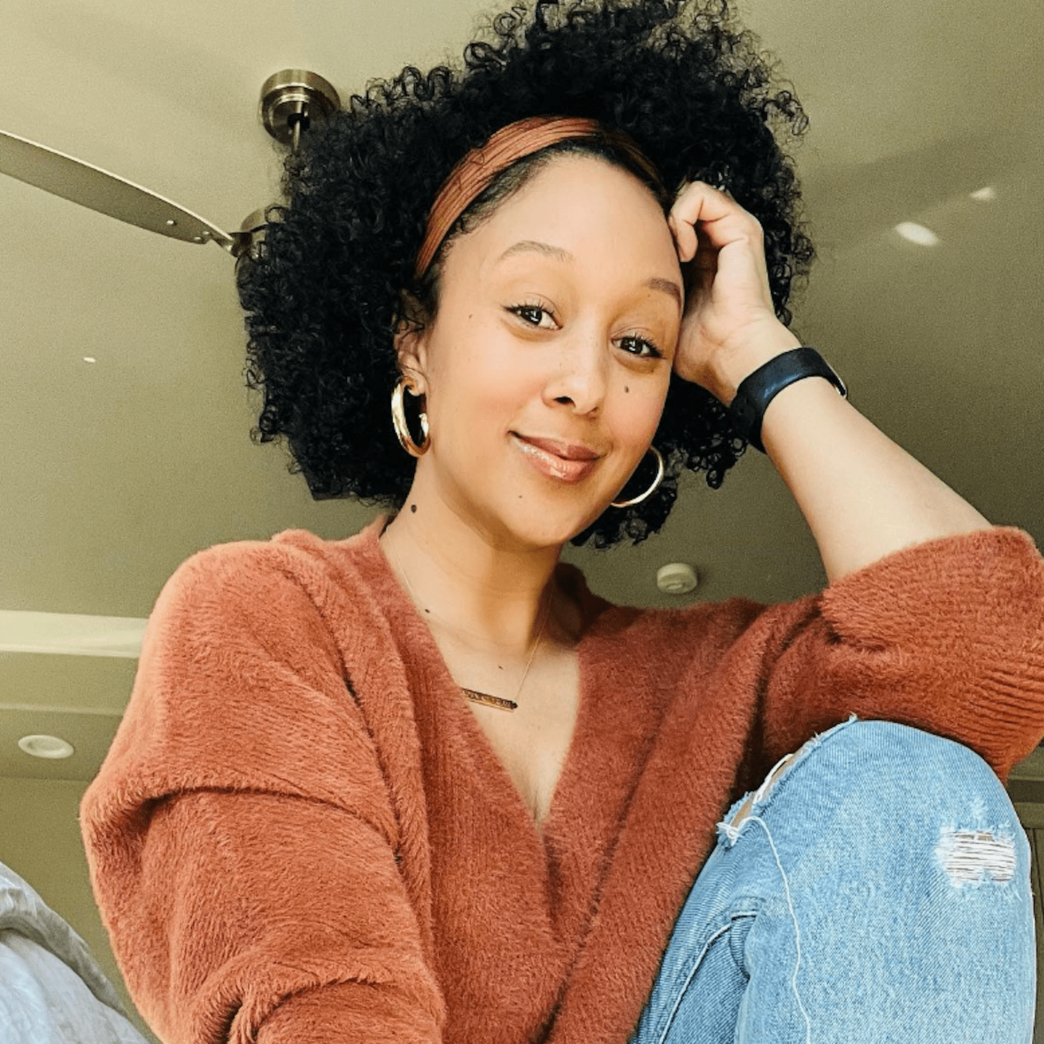 Tamara Mowry wears her natural hair short and off the face with a wrapped headband that matches her burnt orange sweater