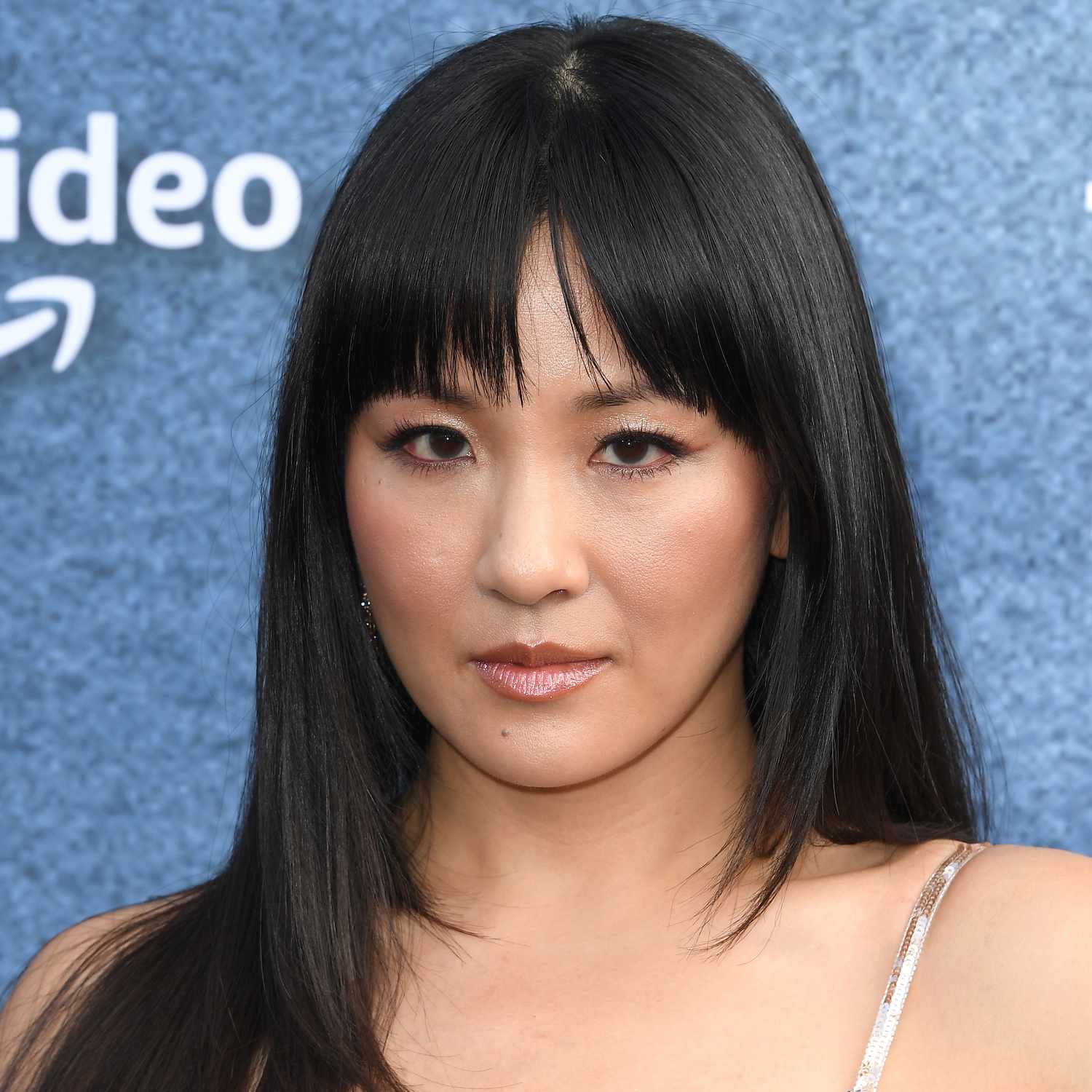 Constance Wu wears a slightly parted french bang with straight hair to a premiere in LA