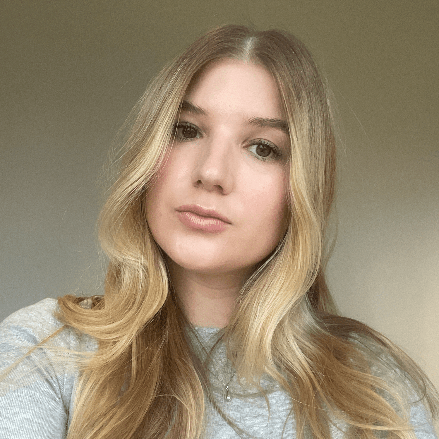 Selfie of a woman with long blonde hair wearing a light grey shirt