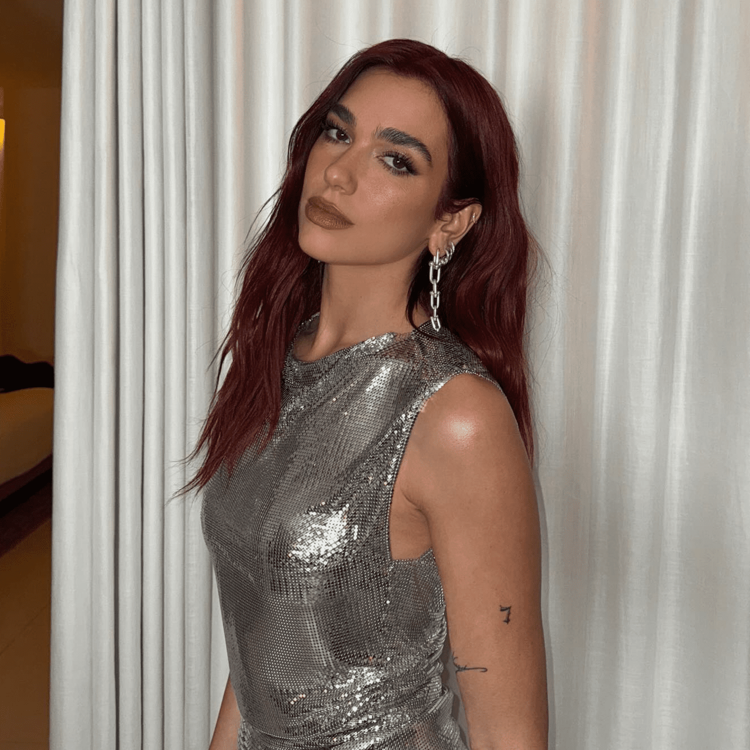 Dua Lipa with wavy, medium-length cherry cola colored-hair.