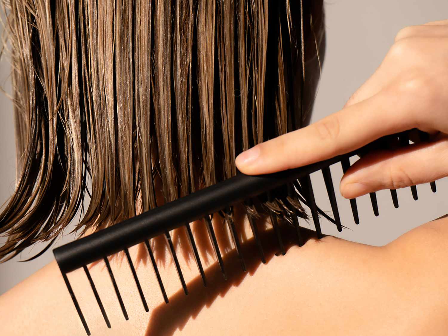 Close-up of wet woman's bob haircut. She is combing it.