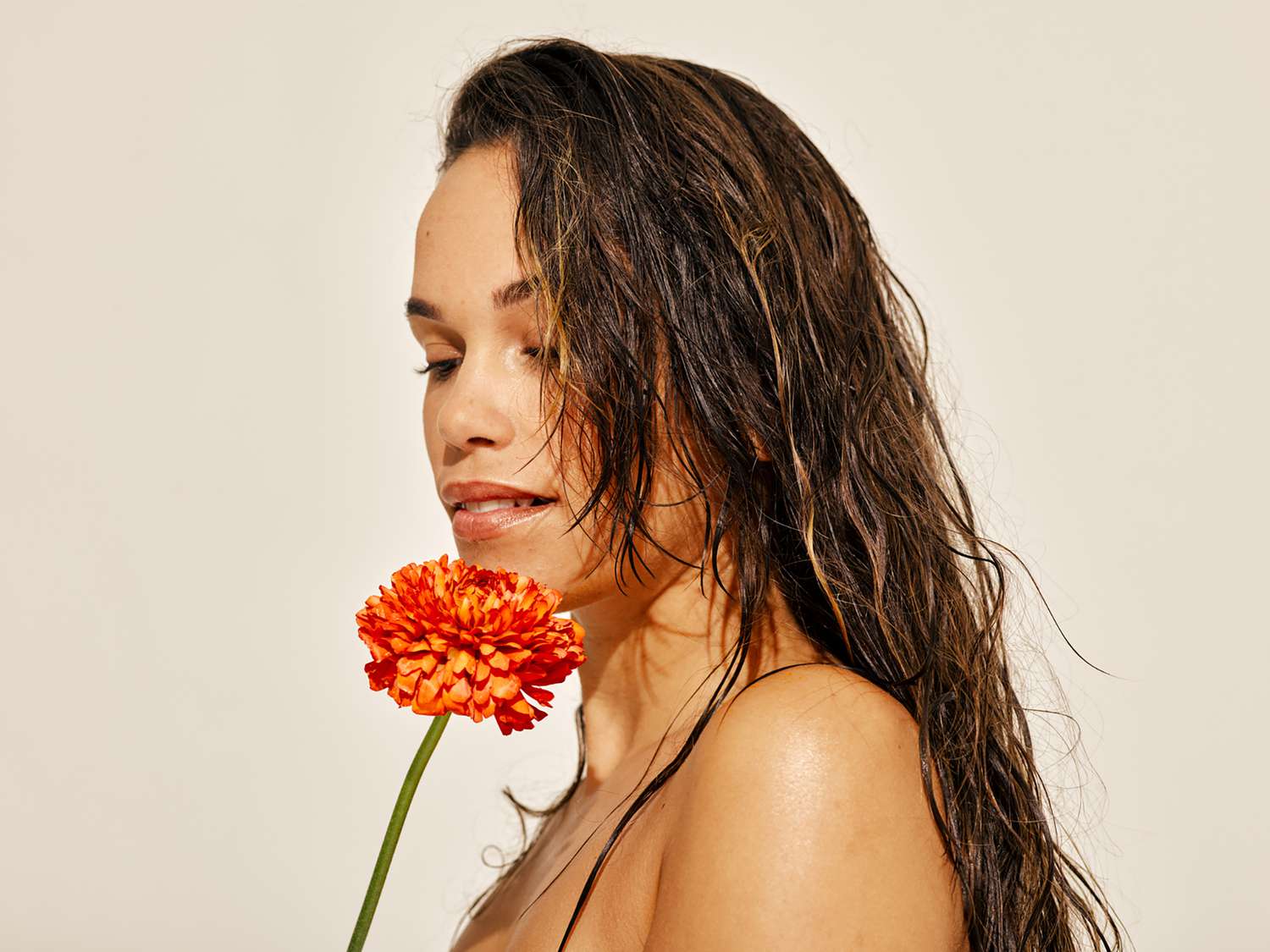 Sunny picture of a woman posing with colorful flower.