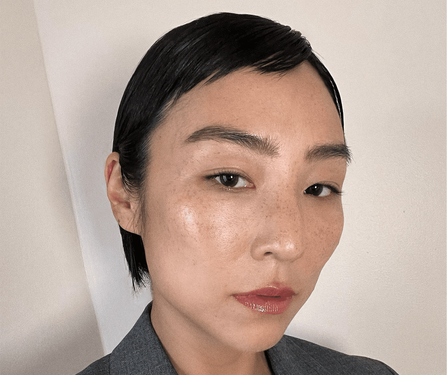 Greta Lee in a grey blazer and pixie cut