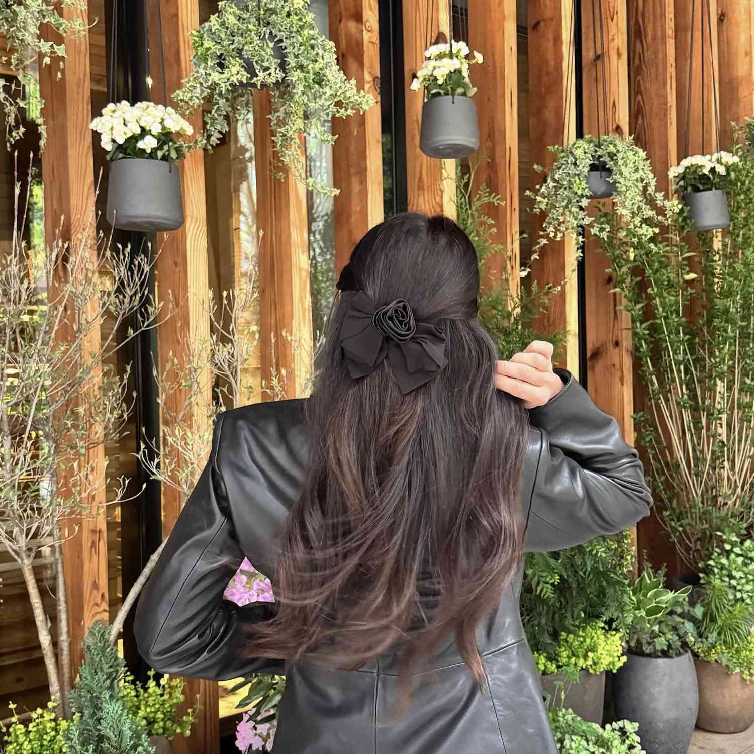 back of woman with dark hair in a half up hairstyle with a black bow